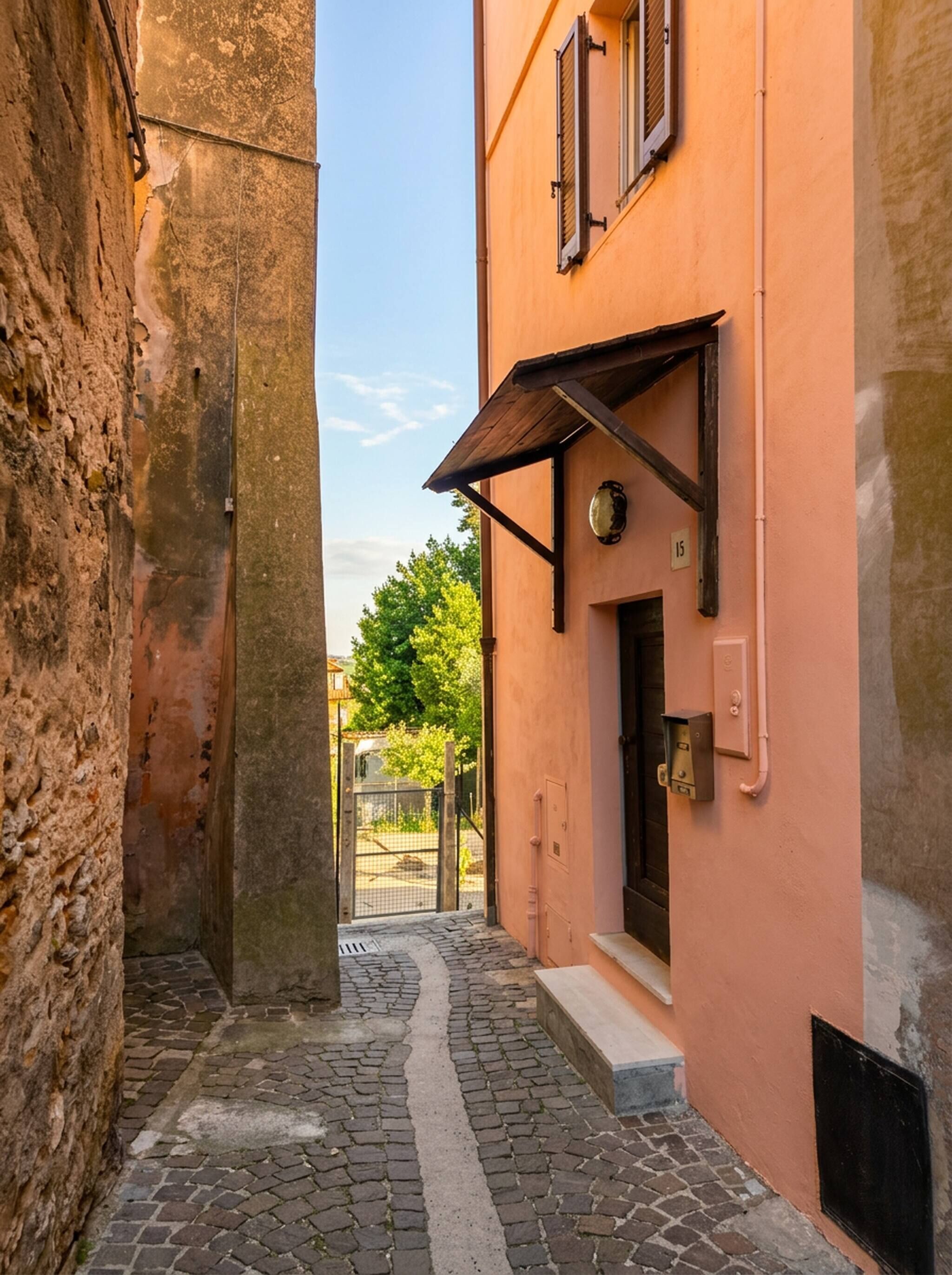 Eine enge Kopfsteinpflasterstraße mit einem Gebäude auf einer Seite und einer Steinmauer auf der anderen.