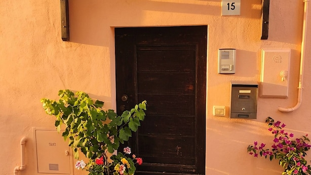 A building entrance with a dark door, a number plaque, a security intercom, and potted plants. - Charming 2-floor Apartment With Vineyard Views in Morro D'alba (Morro d'Alba)