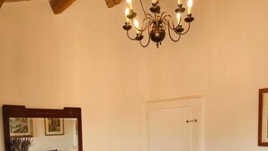 A bedroom with a wooden dresser, a bed with multiple pillows, a chandelier, and a door. - Charming 2-floor Apartment With Vineyard Views in Morro D'alba (Morro d'Alba)