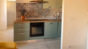 A kitchen with a wooden ceiling, green cabinets, a built-in oven, and pendant lights. - Charming 2-floor Apartment With Vineyard Views in Morro D'alba (Morro d'Alba)