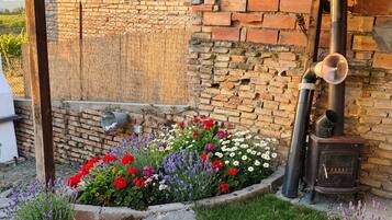 A brick wall with a rustic wooden structure, a stone pathway, and a flower bed with various flowers.