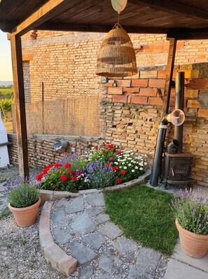 Eine Ziegelwand mit einer rustikalen Holzkonstruktion, ein Steinweg und ein Blumenbeet mit verschiedenen Blumen.