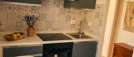 Une cuisine équipée d’un four encastré, d’un évier et d’un coin repas avec une table et des chaises.