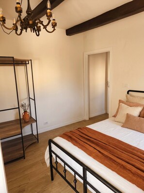 Ein Schlafzimmer mit einem Bett, einer Holzbank, einer Topfpflanze und einem Kronleuchter.