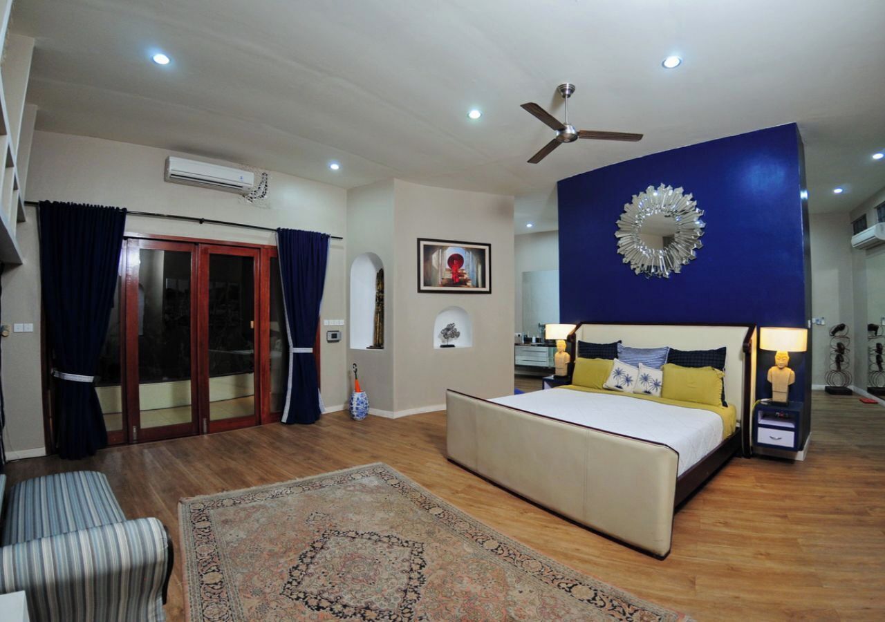A bedroom with a bed, bedside tables, a ceiling fan, and a large decorative mirror.