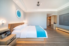 Una habitación de hotel moderna con una cama grande, mesitas de noche, un televisor y un baño a la vista.