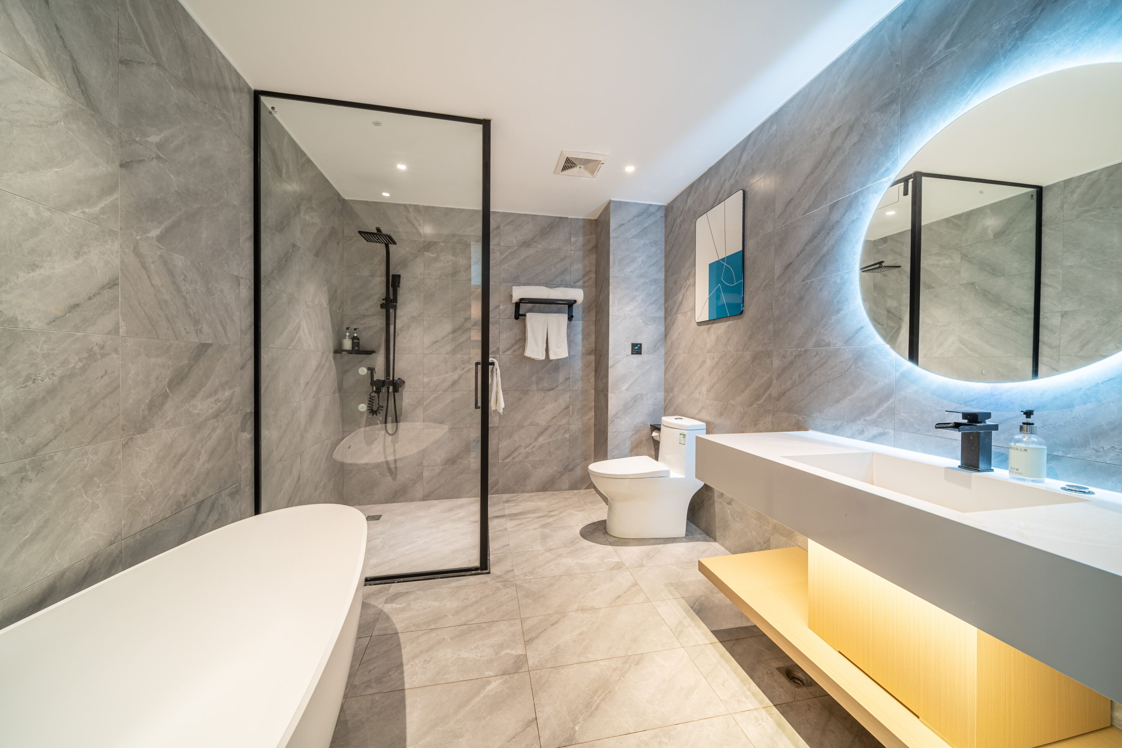 Un baño moderno con ducha a ras de suelo, bañera independiente, un espejo grande y tocador con lavabo.