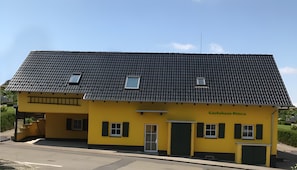 Ein gelbes Gebäude mit einem Ziegeldach, einer Tür und einem Fenster.