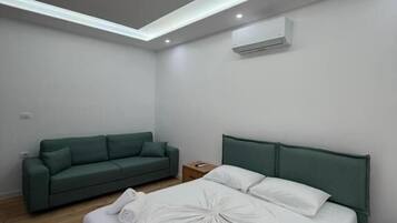 Una camera d'albergo moderna con un letto, un divano verde e una lampada a sospensione.
