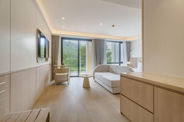Quarto de hotel moderno com sofá, mesa de jantar e cozinha.