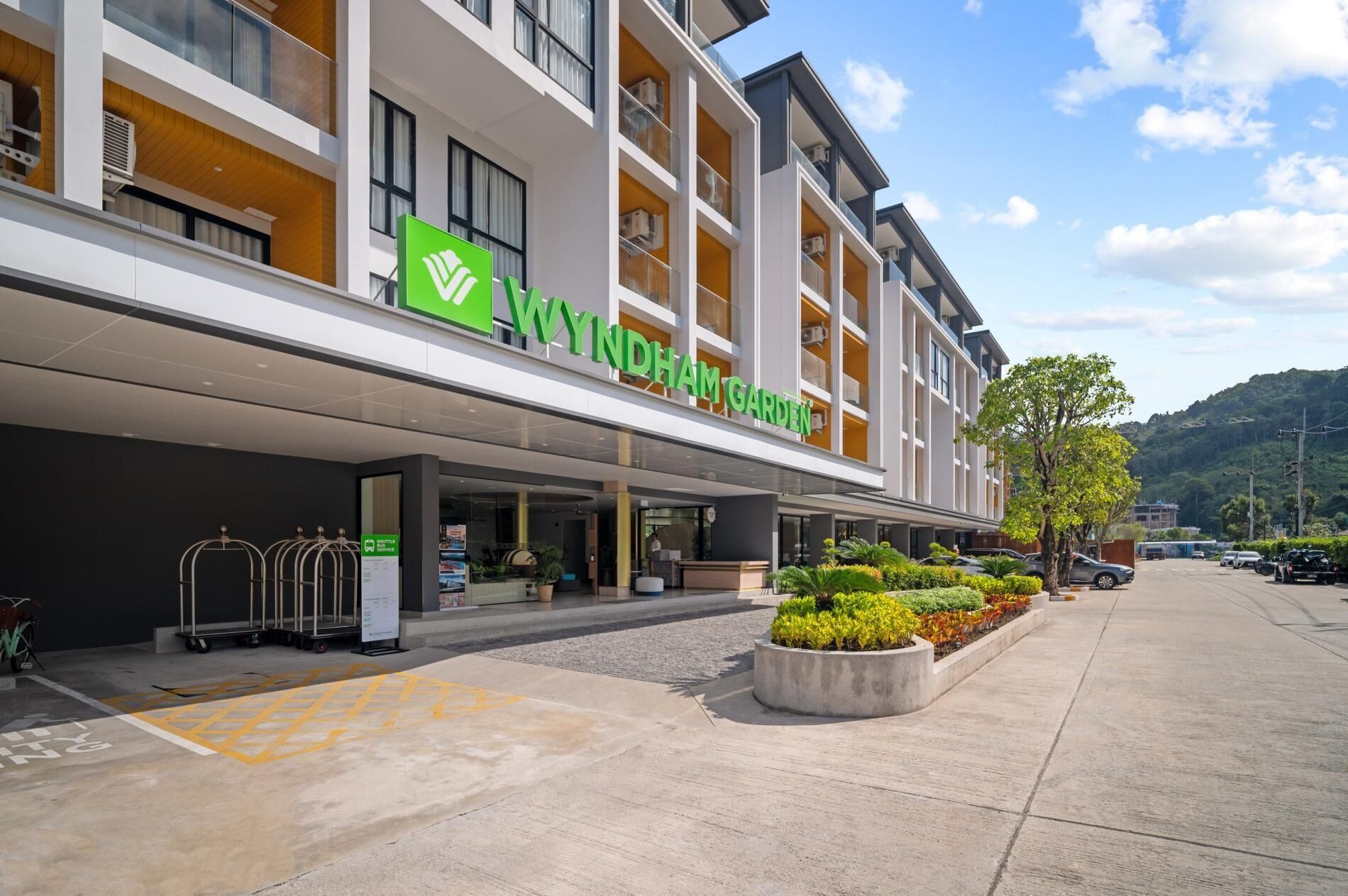 A modern hotel with a green logo, a reception area, and a parking lot.