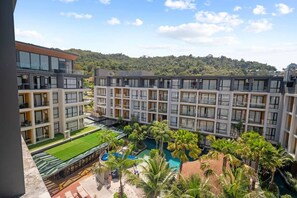 Un hôtel à plusieurs étages doté d’un espace piscine, entouré de palmiers et de verdure.