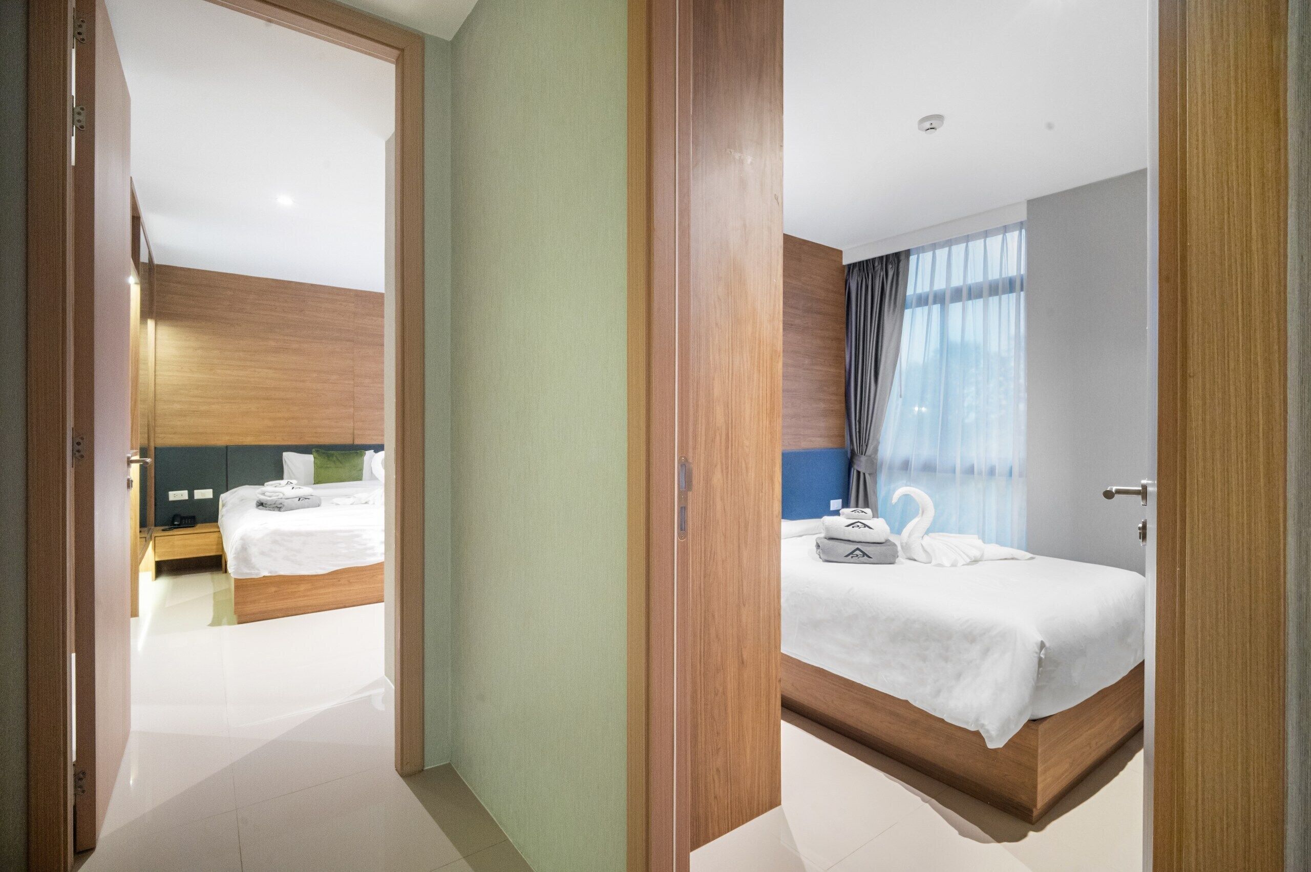 A hotel room with a large bed, a smaller bed, a desk, and a bathroom.