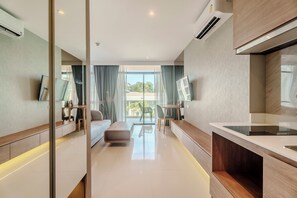 Quarto de hotel moderno com sofá, mesa de jantar, cozinha e uma grande janela com vista para o exterior.