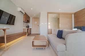 Un salon moderne avec un canapé, une table basse et un téléviseur fixé au mur.