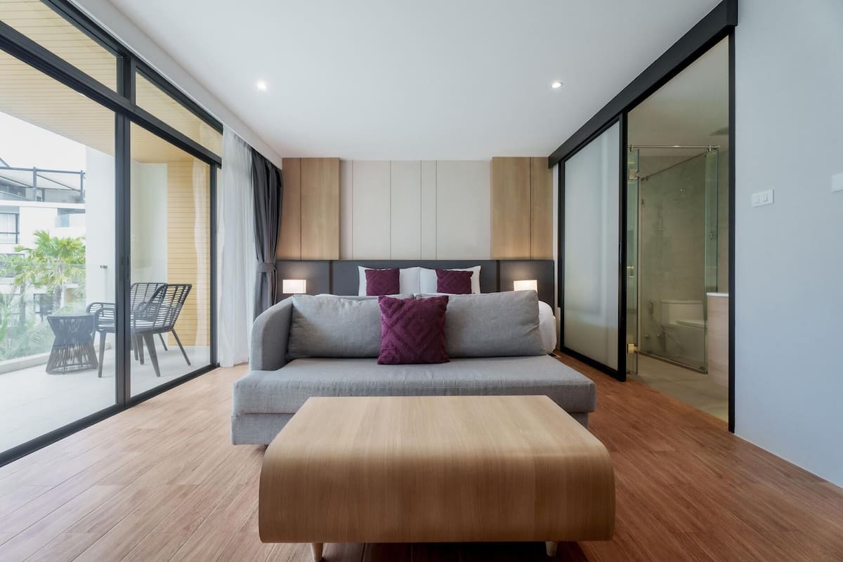 Une chambre moderne avec un canapé-lit, un banc en bois et une cabine de douche en verre.