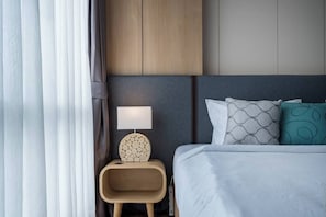 Une chambre d’hôtel avec un lit, une table de chevet avec une lampe et une tête de lit.