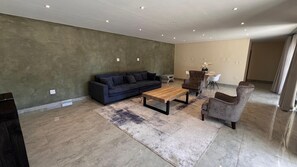 Ein modernes Wohnzimmer mit Sofa, Sessel, Couchtisch und Teppich.