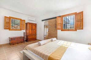 A bedroom with a bed, wooden wardrobe, and two windows with wooden shutters. - Andalusian villa, private pool & mountain views (Loma las Chozas)