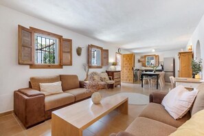 A living room with a sofa, coffee table, and a dining area with chairs and a table. - Andalusian villa, private pool & mountain views (Loma las Chozas)