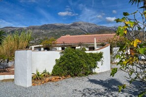 A modern building with a flat roof and a white exterior, surrounded by a gravel area with some greenery. - Andalusian villa, private pool & mountain views (Loma las Chozas)