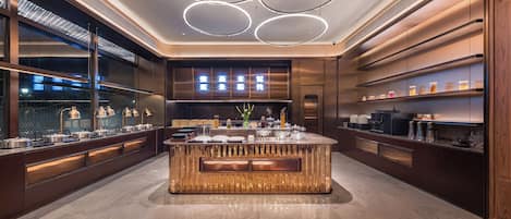 A modern kitchen with a central island, built-in appliances, and a large window.