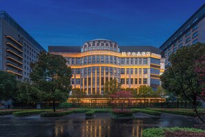 A hotel with a modern architectural design, featuring a curved facade and illuminated signage. - Crystal Hotel Shanghai Hongqiao Qianwan (Shanghai)