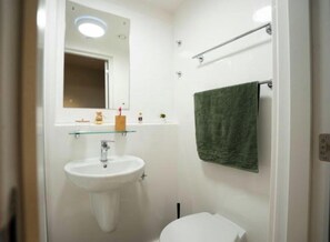 A bathroom with a white sink, a mirror, a towel rack, and a toilet. - Student Only Fusion York (York)