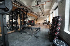 A gym with weightlifting equipment, treadmills, and a wall-mounted dumbbell rack. - Student Only Fusion York (York)
