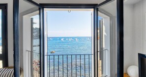 A room with a view of the sea, a balcony with a railing, and a window with a view of boats. - Seafront apartment (Calella de Palafrugell)