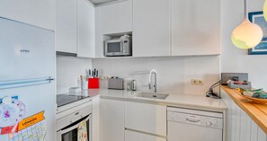 A compact kitchen with white cabinetry, a microwave, a sink, and a Bosch dishwasher. - Seafront apartment (Calella de Palafrugell)