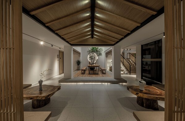 A spacious interior with a high ceiling, wooden beams, a central table with benches, and a staircase. - JIDMI HOTEL (Xiamen)