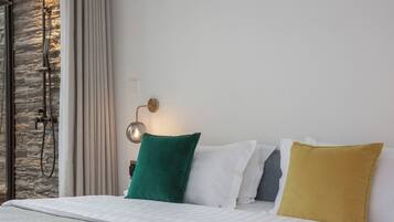A neatly made bed with a white quilt, a green pillow, and a yellow pillow.