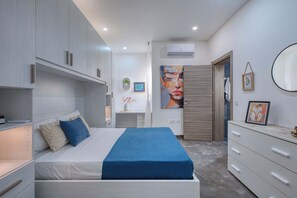 A modern bedroom with a bed, bedside tables, a dresser, and a desk with a chair. - Gozo Sannat Penthouse 3BDR (Sannat)