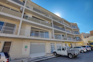 A multi-story building with balconies, a garage door, and a parked truck. - Gozo Sannat Penthouse 3BDR (Sannat)