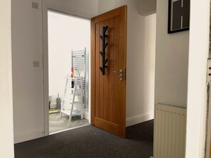 A hallway with a wooden door, a radiator, and a white radiator on the wall. - Walk to Everything | Sleeps 4 | 2 Bed | Bold St (Merseyside)