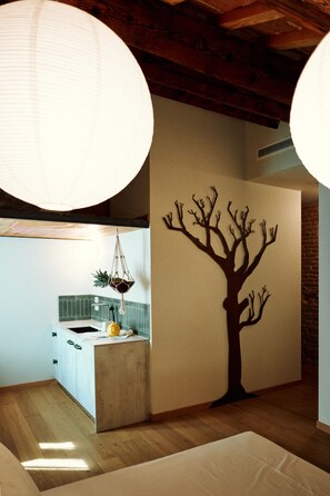A modern kitchen with a central island, pendant lights, and a wall-mounted tree decoration. - Casa Calma | Somewhere Between Venice and Everything Else (Noale)