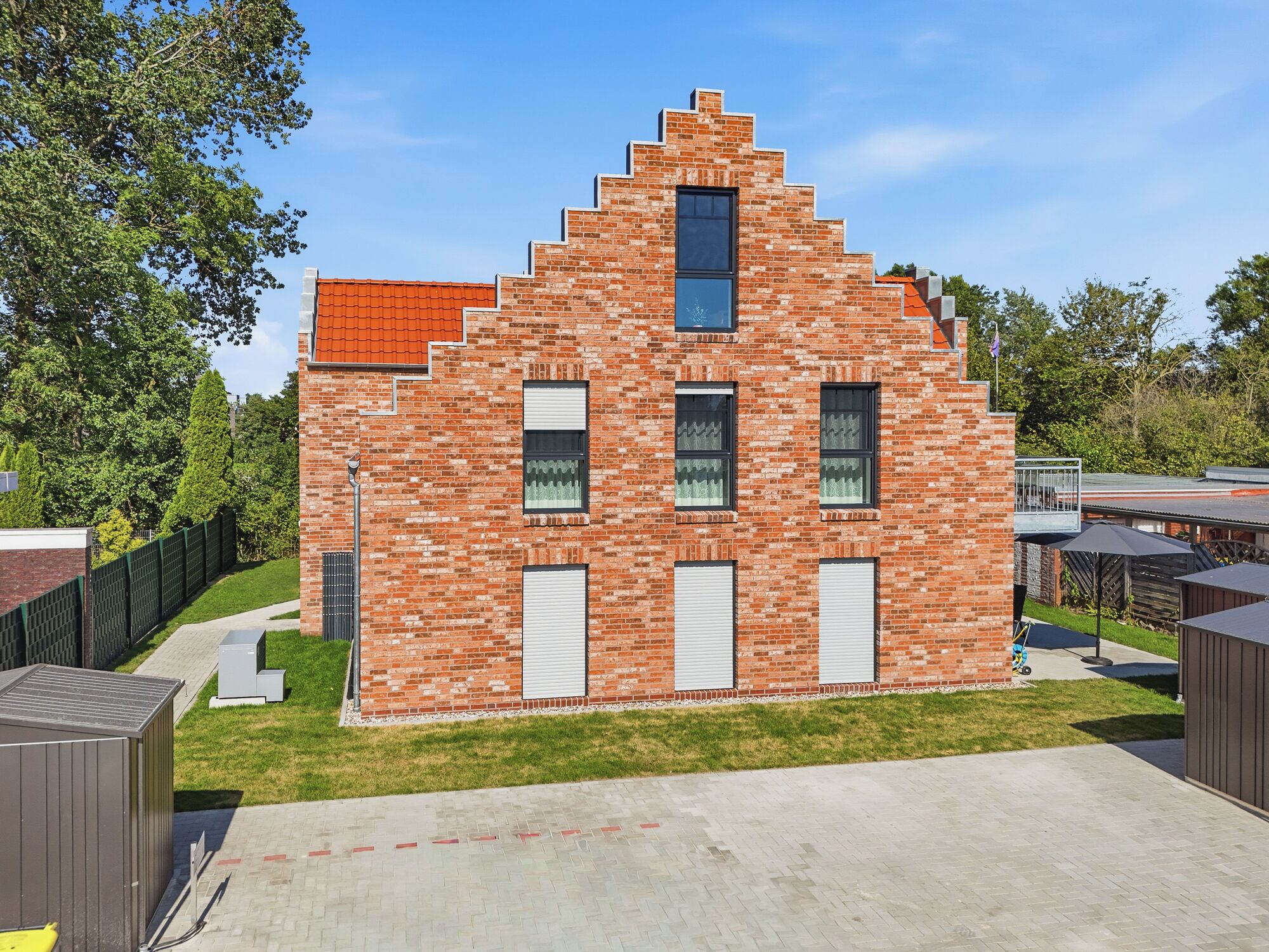 A brick building with a unique stepped roof design, multiple windows, and a small door.