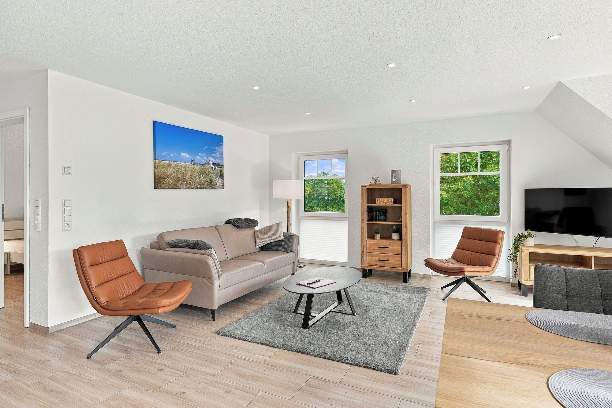 Un salon moderne comprenant un canapé, deux fauteuils, une table basse et un téléviseur.