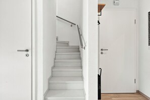 A white interior with a staircase leading to a door. - Lüttje Sünn - Your Oasis of Well-Being in Norddeich (Norddeich)