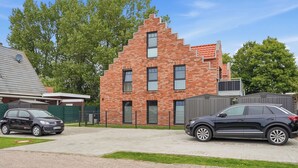 Ein zweistöckiges Backsteinhäuschen mit geneigtem Dach, Garage und befestigter Auffahrt.