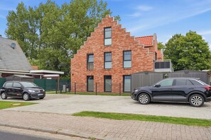 Ett tvåvåningshus byggt av tegel med ett sluttande tak, ett garage och en asfalterad uppfart.