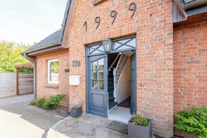 A brick building with a number '1999' on the facade, a front door, and a staircase leading to an upper floor. - Vacation Home "Westerlön Hüs 1999" (Sylt)