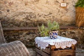 A rustic outdoor setting with a wooden crate table, a lace tablecloth, and a potted plant with blue flowers.
