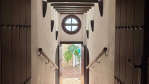 Eine Treppe führt zu einem Raum mit einem Rundfenster und Blick auf eine Palme draußen.