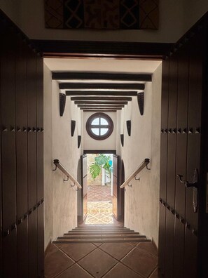 A staircase leading to a room with a circular window and a view of a palm tree outside. - The Courtyard of the Soul (villanueva de la concepción)