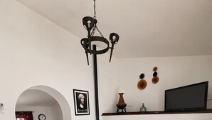 Ein Wohnzimmer mit Sofa, Sesseln, einem Holztisch und einem Fernseher an der Wand.