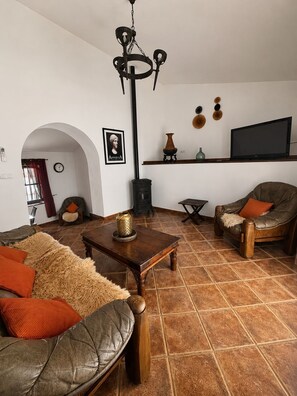 A living room with a sofa, armchair, wooden coffee table, and a TV on a wall. - The Courtyard of the Soul (villanueva de la concepción)