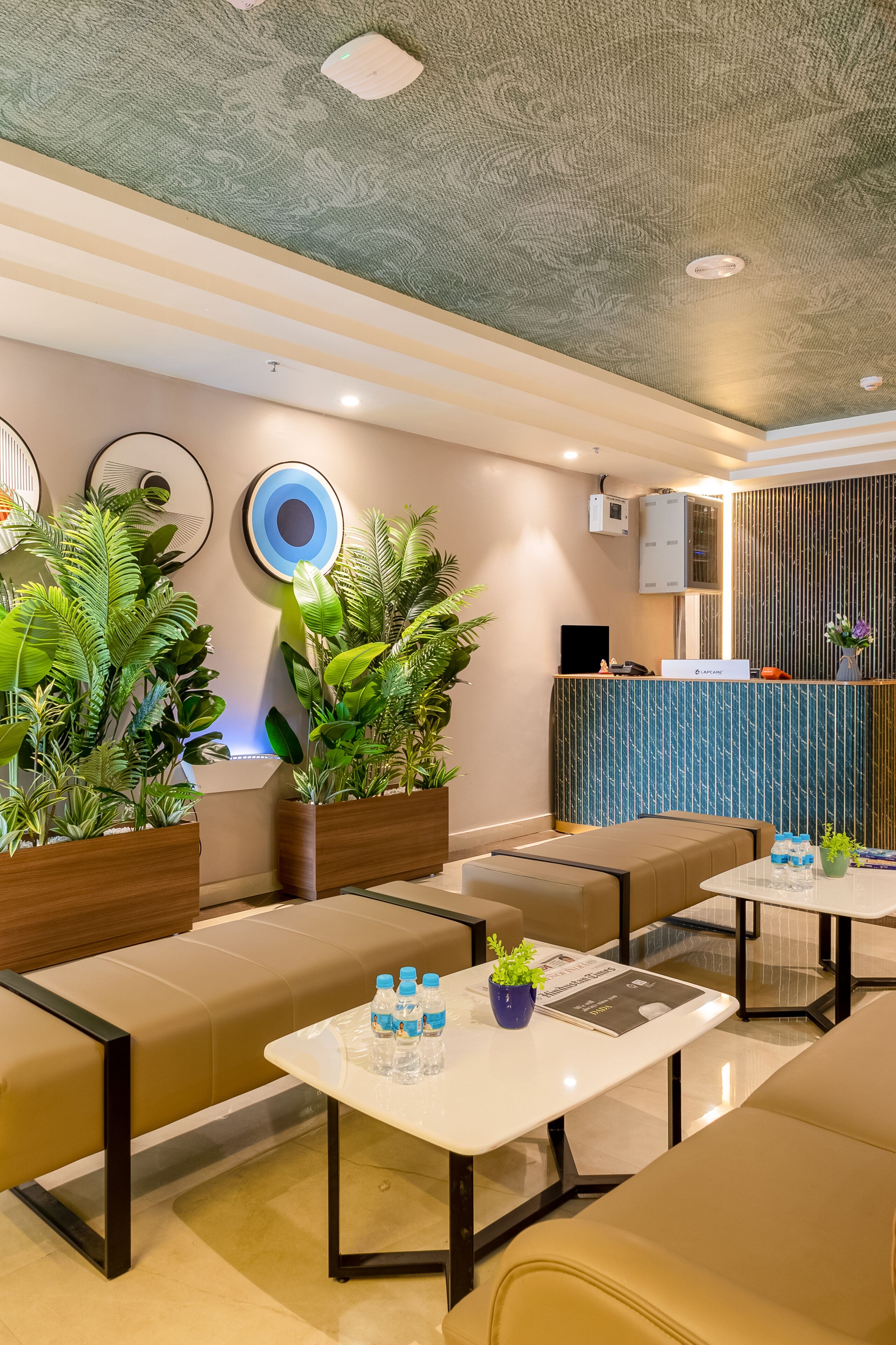 A modern hotel lobby with seating areas, a reception desk, and decorative plants.