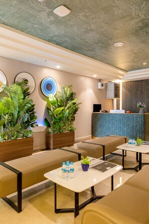 Rebost modern d'un hotel amb zones d'estar, una recepció i plantes decoratives.